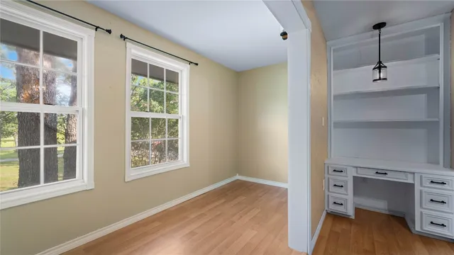 a view of an empty room with a window and wooden floor