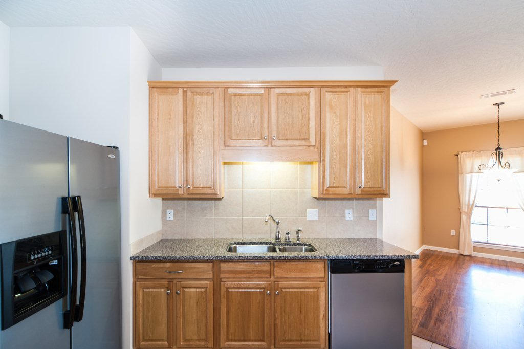 4625 Hermosa Road Crestview, FL 32539 - Photo 13 of 37 a kitchen with granite countertop a refrigerator a sink and wooden cabinets