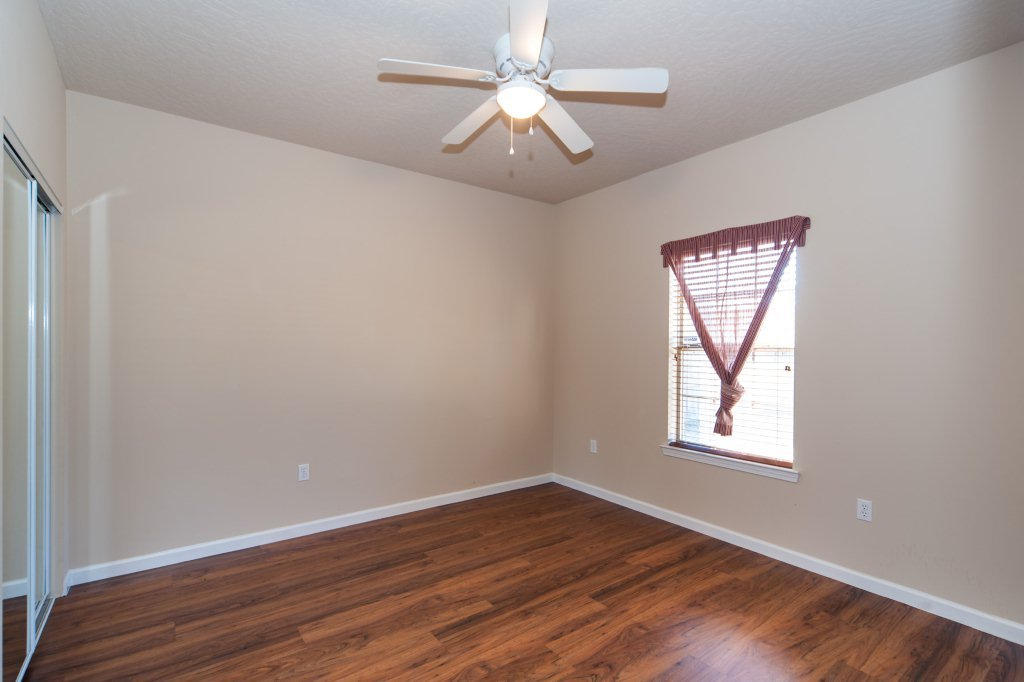4625 Hermosa Road Crestview, FL 32539 - Photo 29 of 37 an empty room with wooden floor chandelier fan and windows