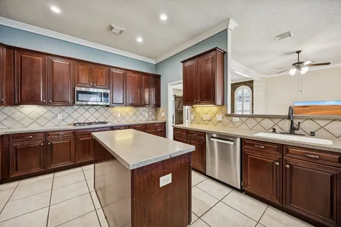 a kitchen with stainless steel appliances kitchen island granite countertop a sink and a wooden cabinets