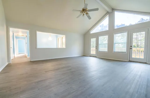 an empty room with wooden floor and windows