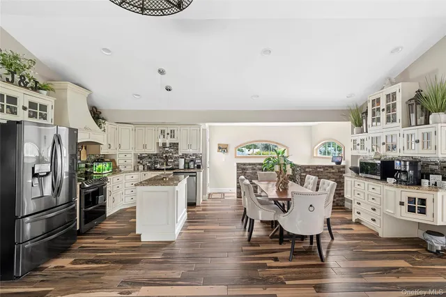a kitchen with stainless steel appliances kitchen island granite countertop a table chairs stove and refrigerator