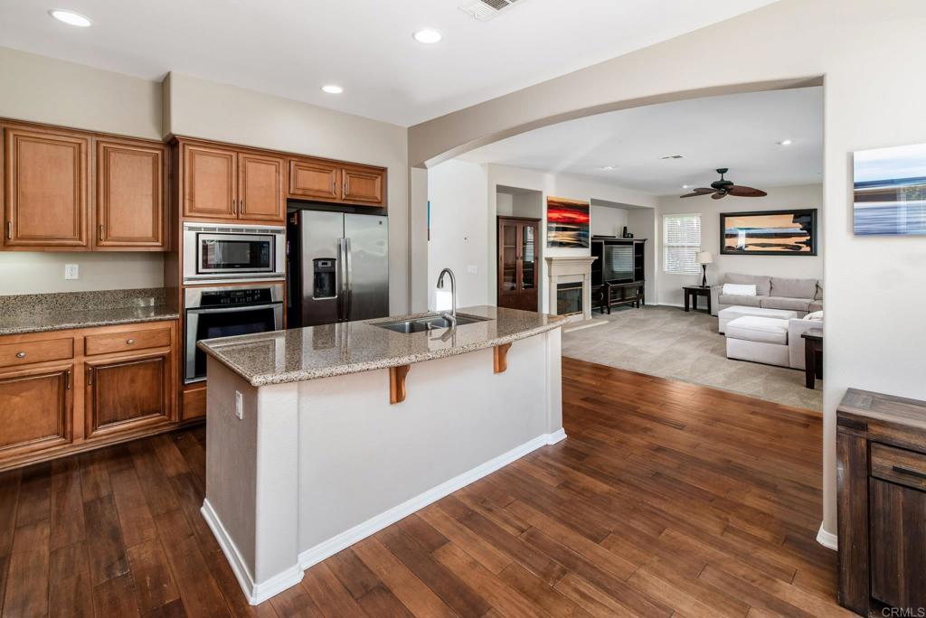 3434 Ravine Drive Carlsbad, CA 92010 - Photo 7 of 37 a large kitchen with stainless steel appliances wooden floors and wooden cabinets