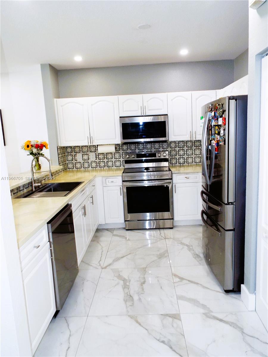 21470 Southwest 85th Path Cutler Bay, FL 33189 - Photo 11 of 50 a kitchen with stainless steel appliances granite countertop a sink stove and refrigerator
