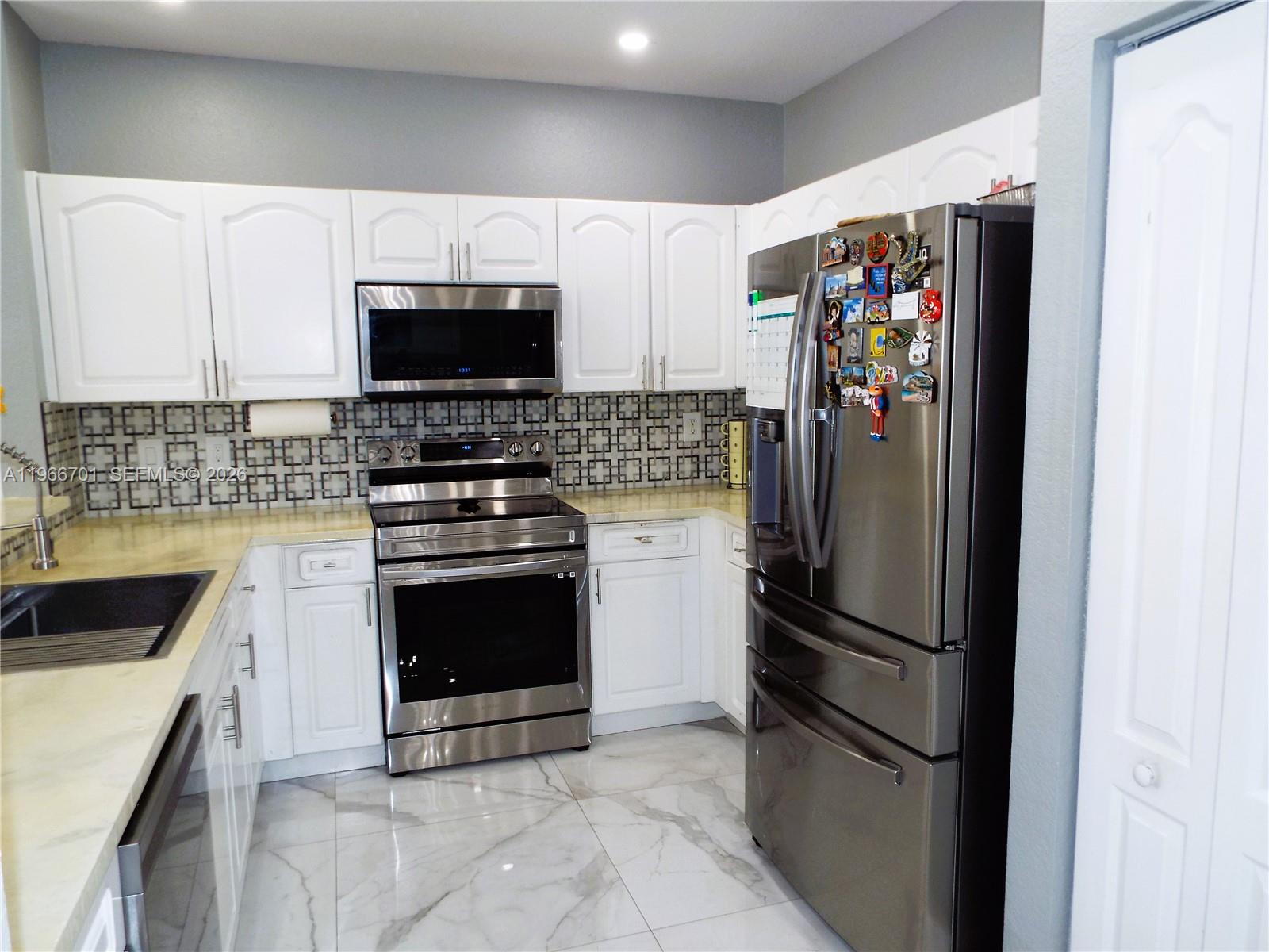 21470 Southwest 85th Path Cutler Bay, FL 33189 - Photo 12 of 50 a kitchen with stainless steel appliances granite countertop a refrigerator stove and microwave