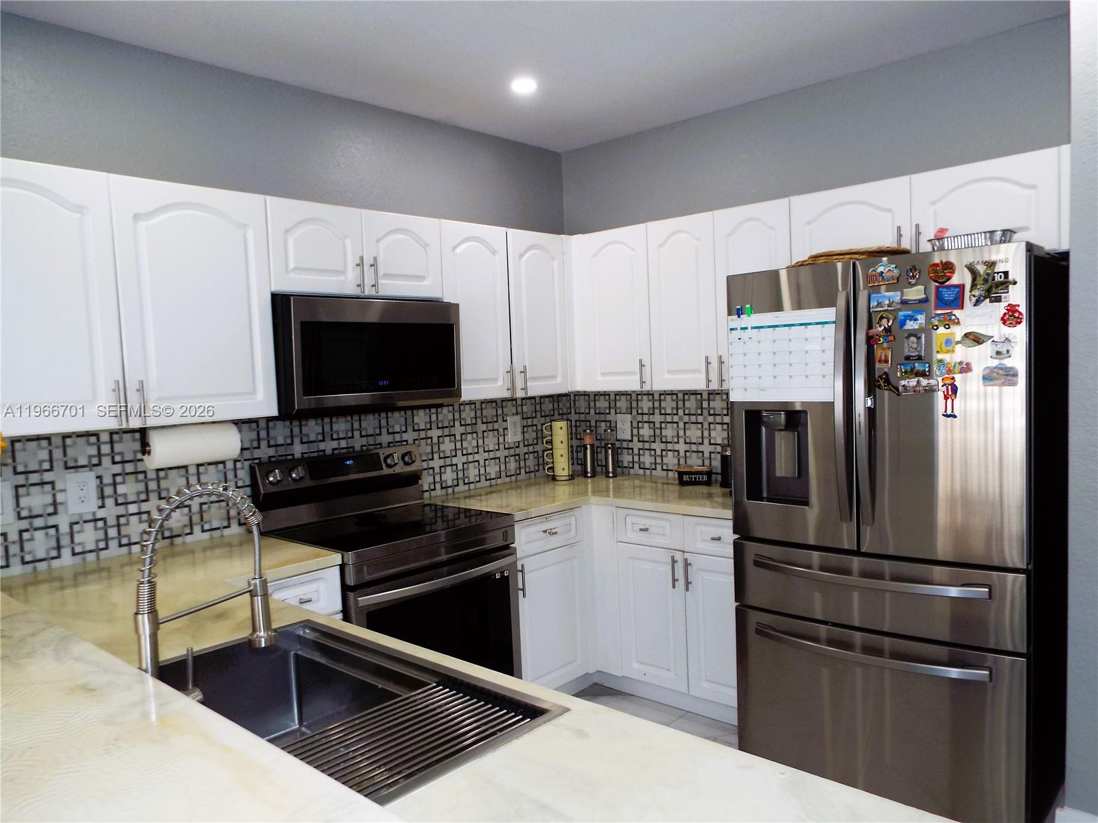 21470 Southwest 85th Path Cutler Bay, FL 33189 - Photo 13 of 50 a kitchen with stainless steel appliances a refrigerator a stove a sink and a microwave