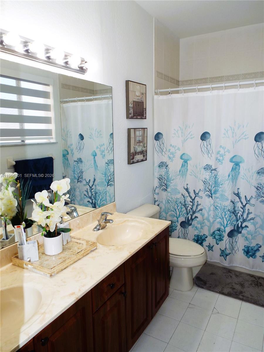 21470 Southwest 85th Path Cutler Bay, FL 33189 - Photo 40 of 50 a bathroom with a sink a toilet and shower curtain
