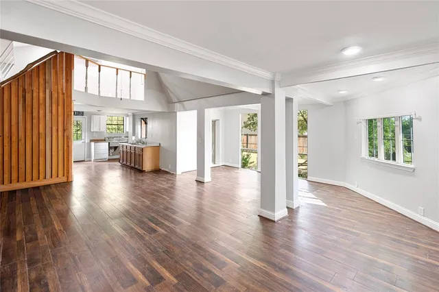 an empty room with wooden floor chandelier fan and windows