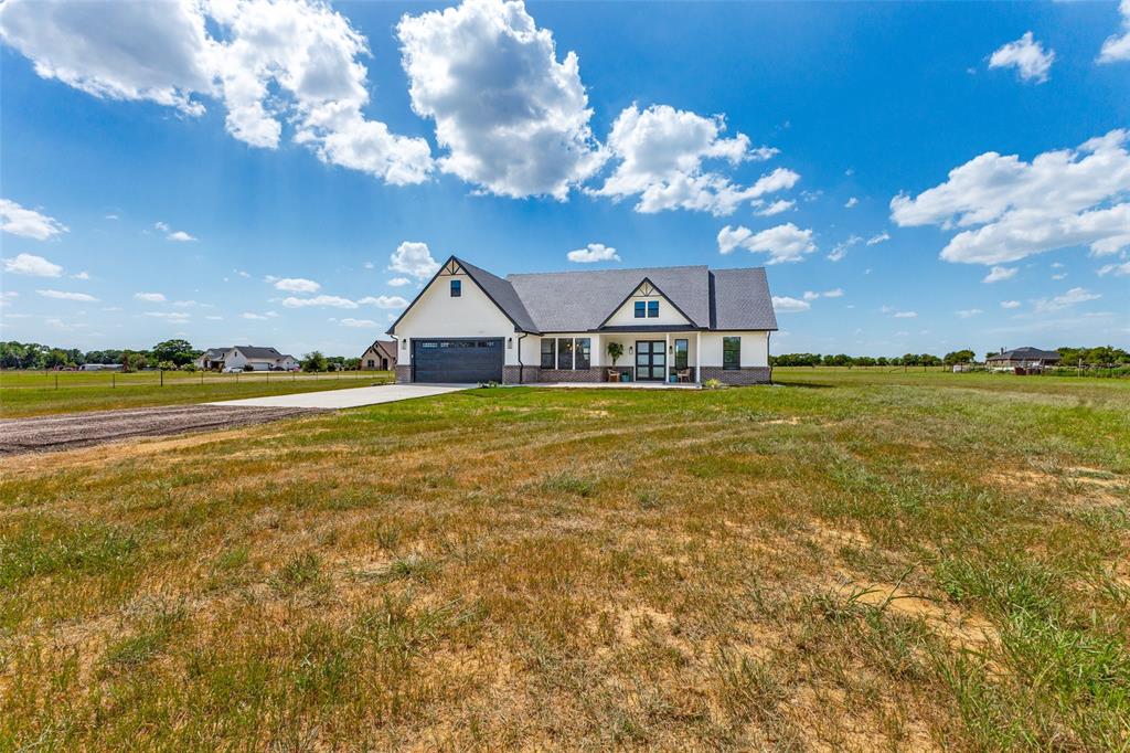 3150 Crisp Road Ennis, TX 75119 - Photo 28 of 30 Modern farmhouse-style residence featuring a prominent gabled roofline and an attached garage with a dark panel door