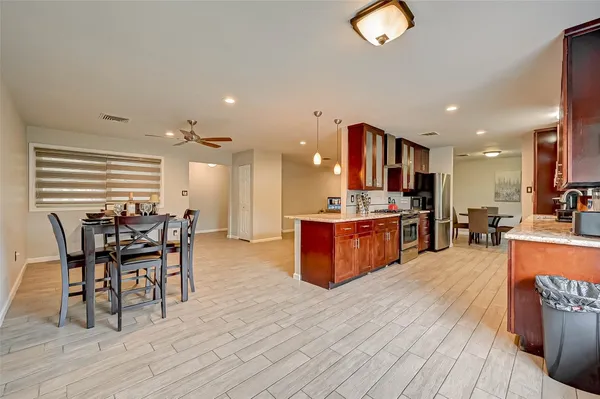 a kitchen with stainless steel appliances kitchen island granite countertop a table chairs and a wooden cabinets