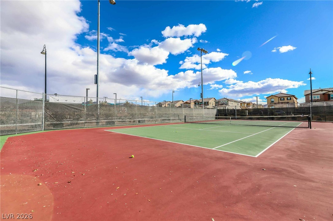 2166 Trivero Street Henderson, NV 89044 - Photo 59 of 61 A vibrant tennis court awaits, bordered by homes under a striking blue sky.