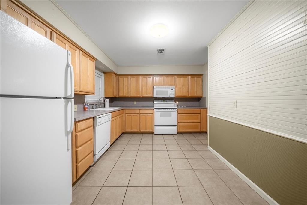 101 North 7th Street Krum, TX 76249 - Photo 16 of 26 Kitchen featuring white appliances, light tile patterned floors, light countertops, and light brown cabinets