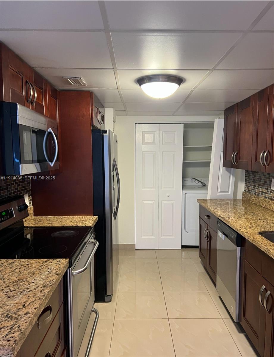 3928 Southwest 67th Way, Unit 97 Davie, FL 33314 - Photo 5 of 9 a kitchen with stainless steel appliances granite countertop a stove a sink and a microwave