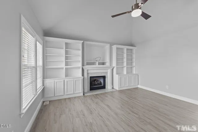 an empty room with windows and fireplace