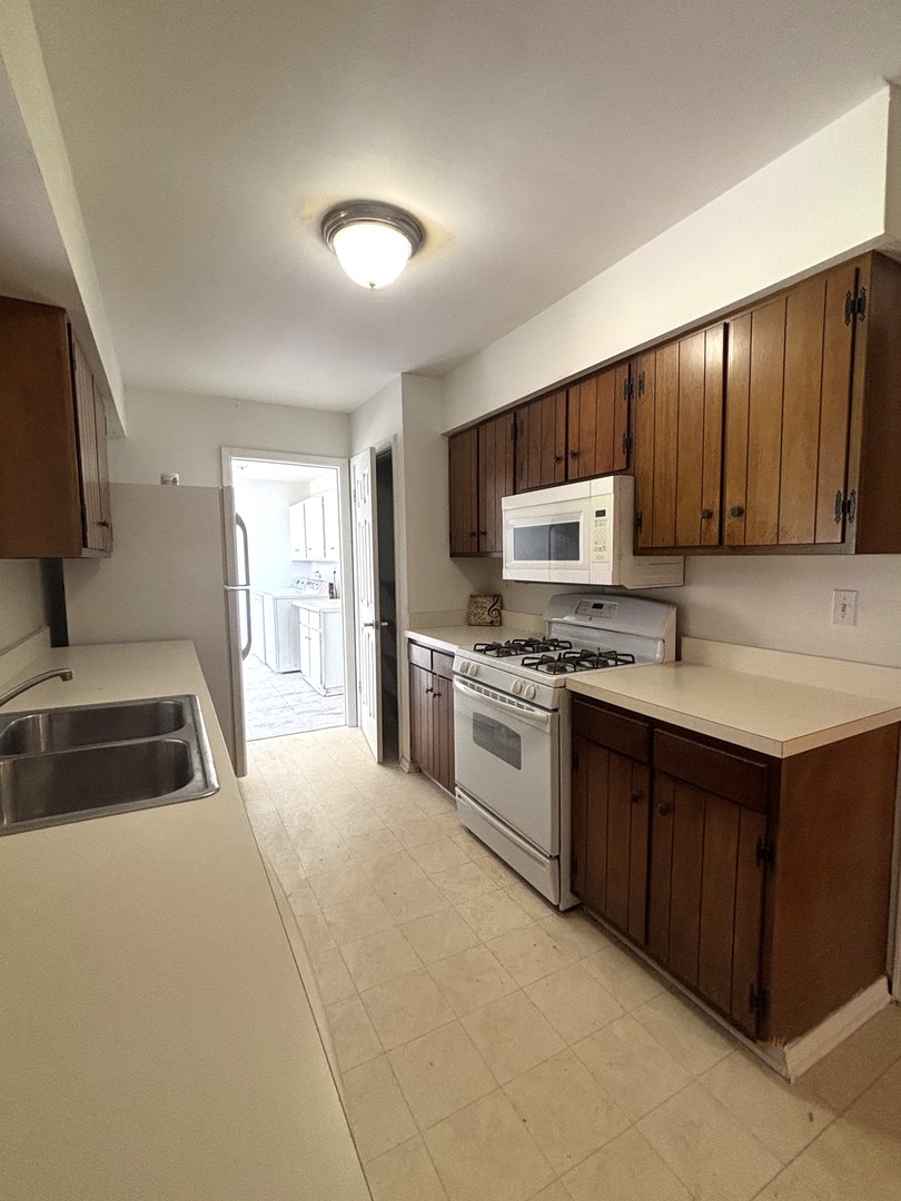 22 Guilford Road Montgomery, IL 60538 - Photo 5 of 14 a kitchen with granite countertop a sink a stove top oven a refrigerator with wooden cabinets and floor