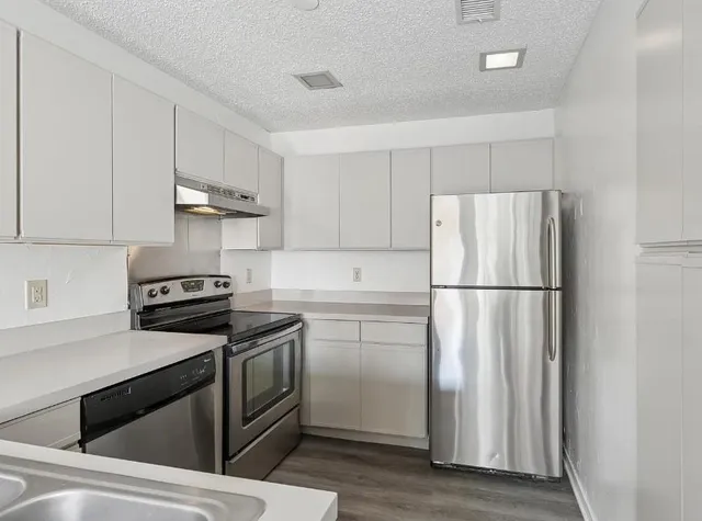 a kitchen with cabinets stainless steel appliances and wooden floor