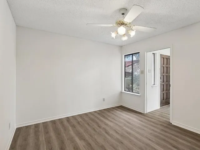 an empty room with wooden floor chandelier fan and closet area