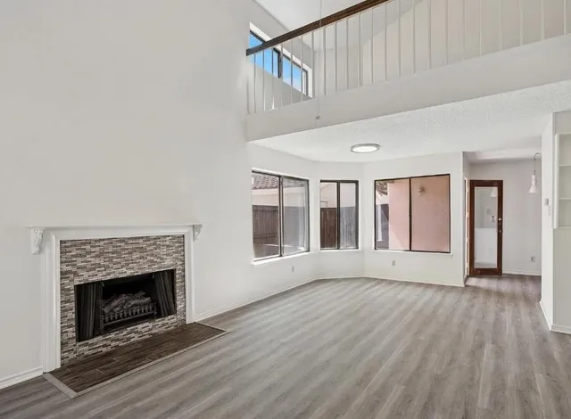 a view of an empty room with wooden floor fireplace and a window