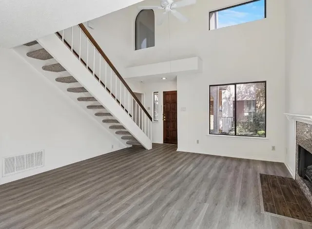 a view of an empty room with wooden floor and stairs