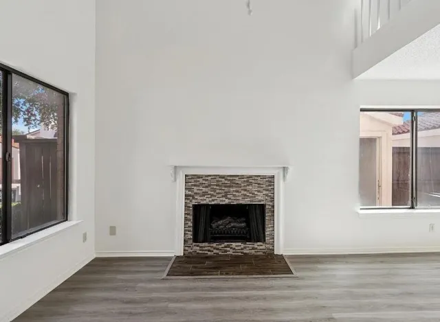 a view of an empty room with wooden floor fireplace and a window