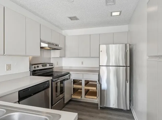 a kitchen with a refrigerator stove and wooden floor