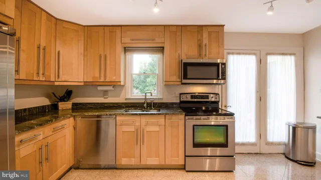 a kitchen with stainless steel appliances granite countertop a stove a sink and a microwave