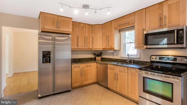 a kitchen with stainless steel appliances granite countertop a refrigerator a stove a sink and a microwave