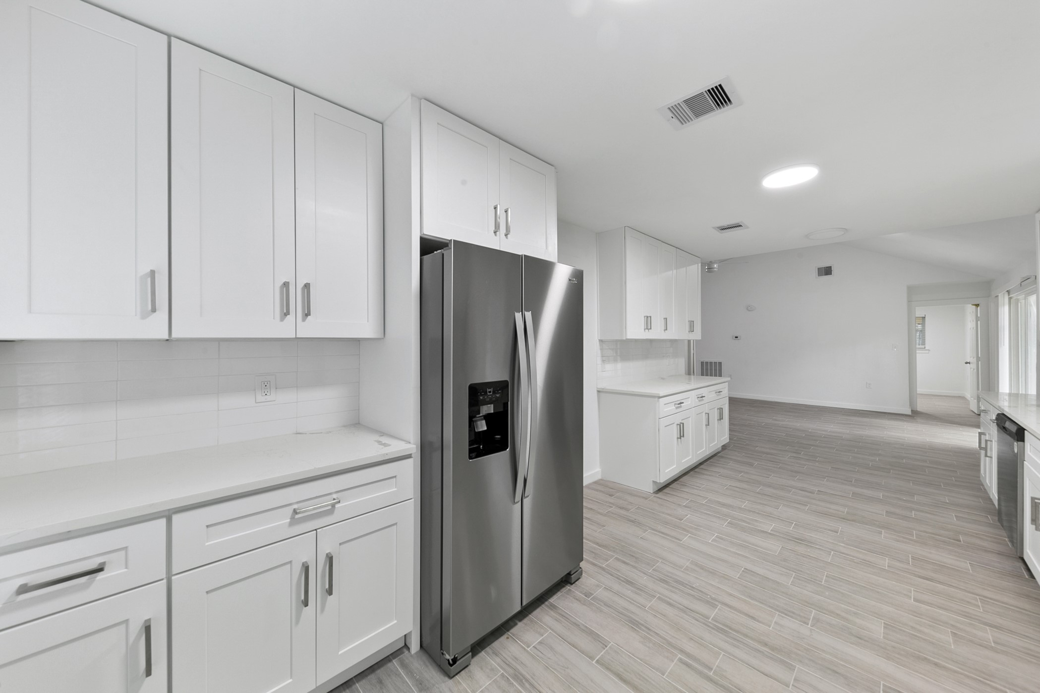 6811 McCullum Road Houston, TX 77489 - Photo 7 of 22 This modern kitchen features sleek white cabinetry, stainless steel appliances, and light wood-style flooring. The open layout offers ample space and natural light, creating a bright and inviting atmosphere.