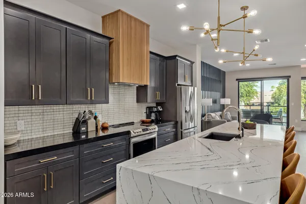 a kitchen with stainless steel appliances kitchen island granite countertop a refrigerator a sink dishwasher a stove and a refrigerator with wooden floor