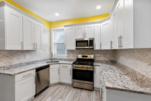 a kitchen with stainless steel appliances granite countertop a stove a sink and a microwave