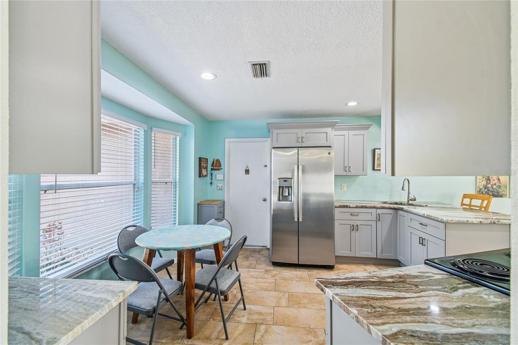 13170 Pirate Lane Spring Hill, FL 34609 - Photo 11 of 83 a kitchen with stainless steel appliances granite countertop a table chairs and a refrigerator