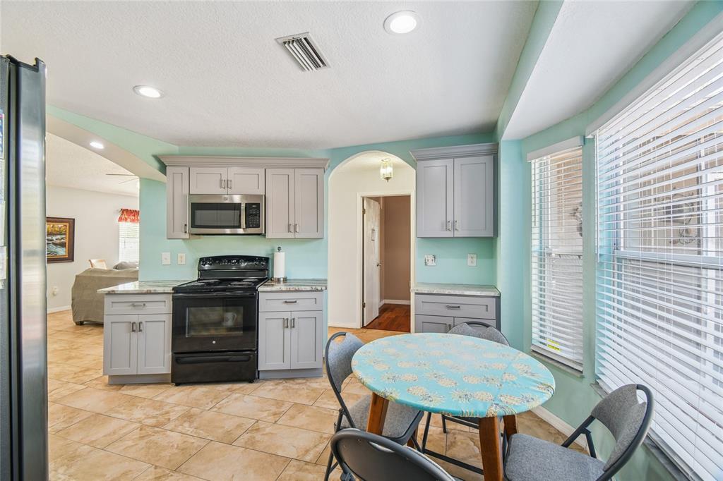 13170 Pirate Lane Spring Hill, FL 34609 - Photo 12 of 83 a kitchen with stainless steel appliances granite countertop a stove top oven a sink dishwasher a dining table and chairs with wooden floor