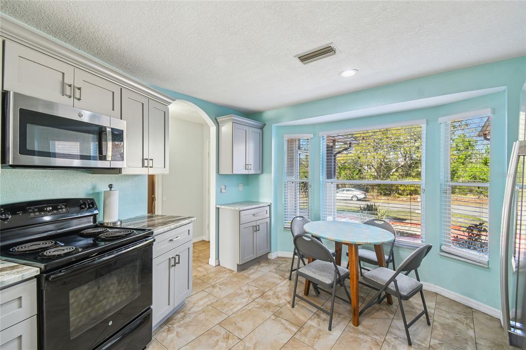 13170 Pirate Lane Spring Hill, FL 34609 - Photo 13 of 83 a kitchen with stainless steel appliances granite countertop a stove top oven a sink dishwasher a dining table and chairs with wooden floor