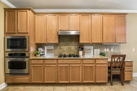 a kitchen with stainless steel appliances granite countertop a stove a sink and white cabinets