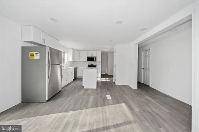 a view of a kitchen with a refrigerator a stove top oven and cabinets
