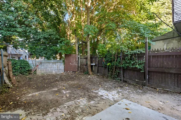 a backyard of a house with large trees and wooden fence
