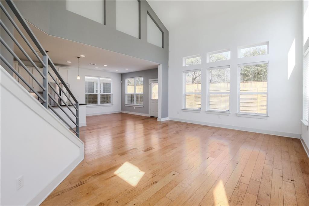 5809 Swayden Lane Austin, TX 78745 - Photo 4 of 10 Open-concept living area with 22" high ceilings, wood-finish flooring, and multiple windows providing natural illumination