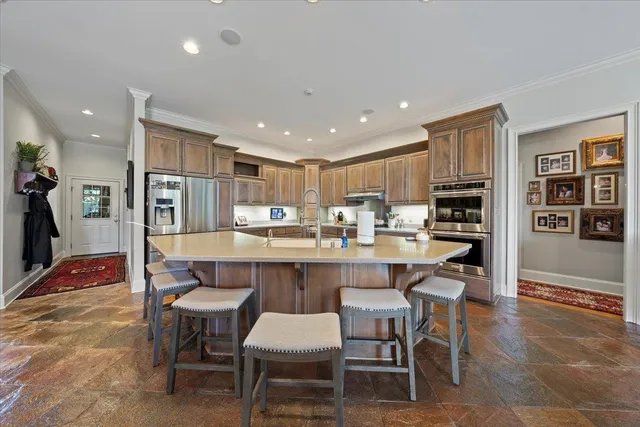 a kitchen with stainless steel appliances granite countertop a dining table chairs refrigerator and sink