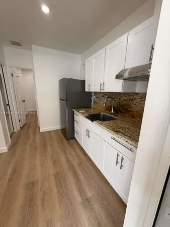 a kitchen with a sink a refrigerator and cabinets