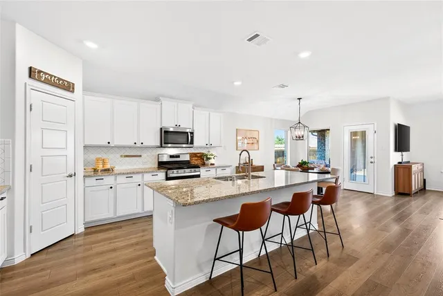 a kitchen with granite countertop a sink stove top oven and cabinets