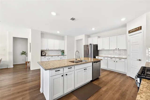 a kitchen with a sink a stove a refrigerator and white cabinets