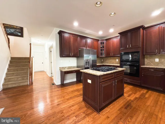 a kitchen with stainless steel appliances granite countertop a refrigerator and a stove top oven