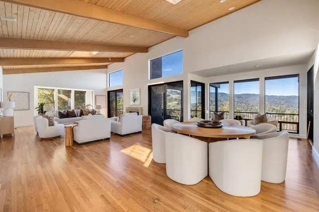 a view of a living room kitchen with furniture and large windows