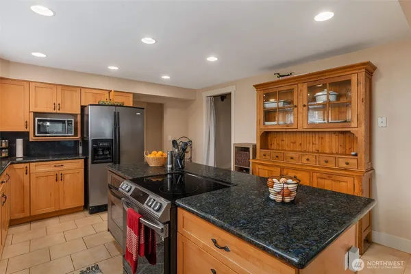 a kitchen with stainless steel appliances granite countertop a sink a stove and a refrigerator