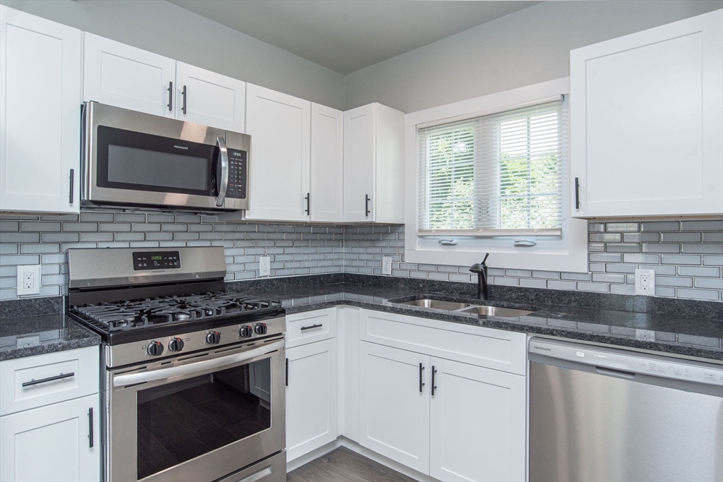 260 High Street Cumberland, RI 02864 - Photo 5 of 42 a kitchen with granite countertop white cabinets appliances and a window
