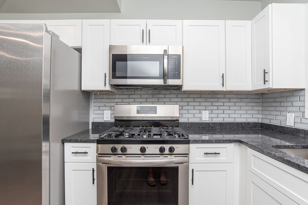 260 High Street Cumberland, RI 02864 - Photo 7 of 42 a kitchen with stainless steel appliances wooden cabinets and a stove top oven