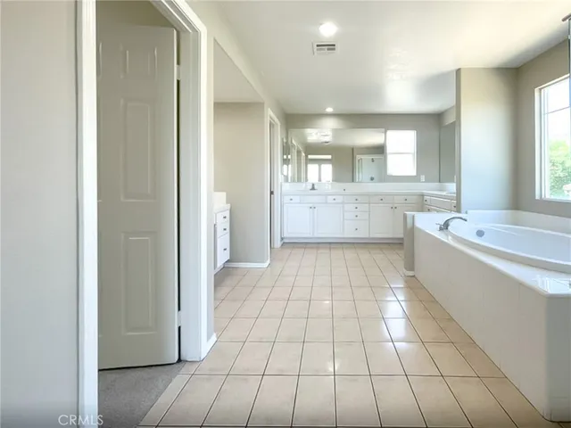 a spacious bathroom with a tub sink and mirror