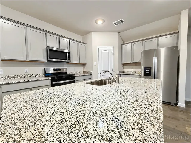 a kitchen with stainless steel appliances granite countertop a refrigerator a stove top oven a sink and cabinets