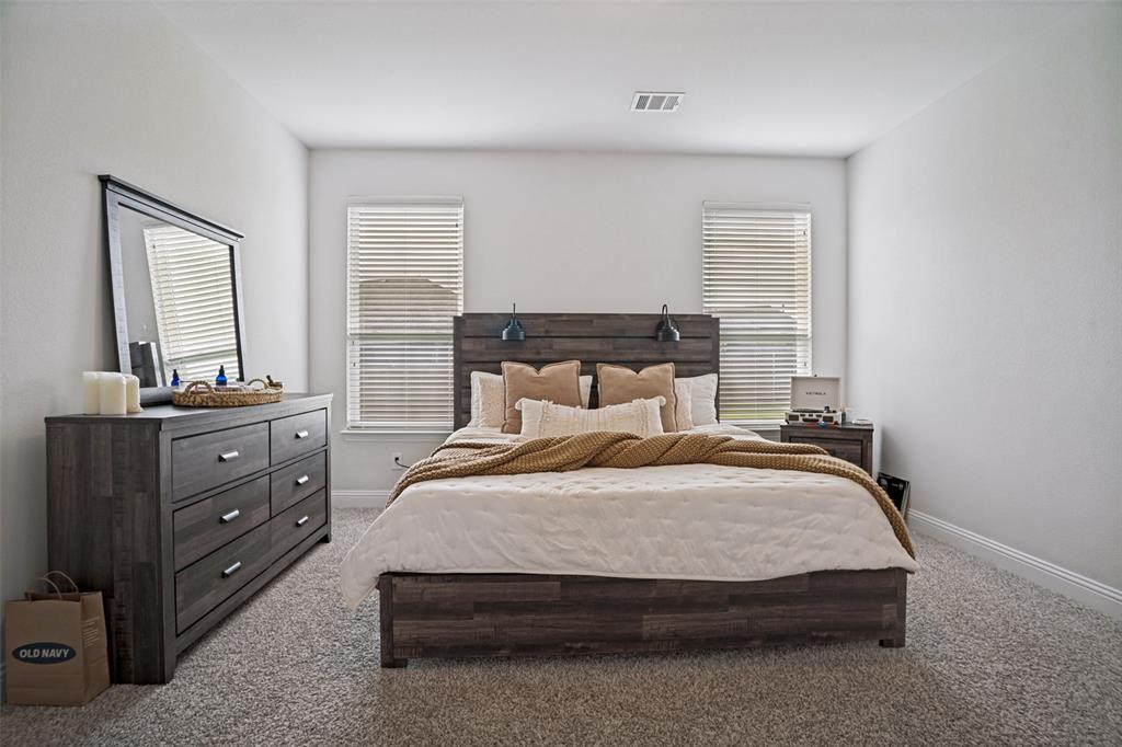 3115 Giovanni Point Princeton, TX 75407 - Photo 18 of 26 Bedroom featuring neutral-toned walls, two windows with blinds, and light gray carpeting