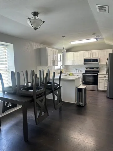 a kitchen with kitchen island a stove a table and chairs in it